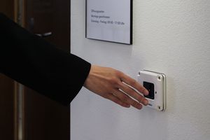Person hält Hand vor Sensor um die Türe zum Lesesaal zu öffnen.
